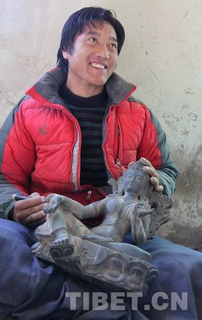 Tubdian Gyamtso, an engraver of black boulder carving shows an exquisite piece of his works. [Photo/China Tibet Online]