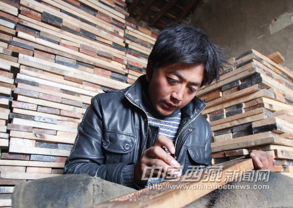 Villager Tsering works carefully on his wood carving in Phusum, southwest Lhasa's Nyemo County, on Apr.4. [Photo/China Tibet News]