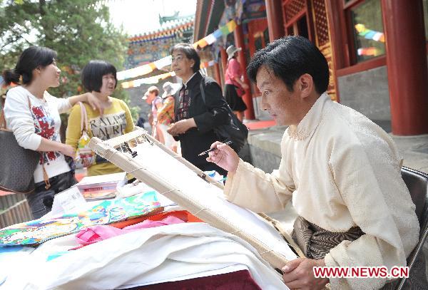 A craftsman paints tangka in Prince Gong's Mansion in Beijing, capital of China, May 10, 2011. The exhibition exhibited over 100 tangkas, the Tibetan silk painting with embroidery, lasting until July 11. [Photo/Xinhua]