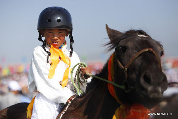 A youngster riding his horse enters the race course during the opening ceremony of the 5th Gesar horse racing in Maqu County, Gannan Tibetan Autonomous Prefecture, northwest China's Gansu Province, Aug. 13, 2011. A total of 12 teams in Maqu will compete in the five-day horse racing. [Photo/Xinhua]