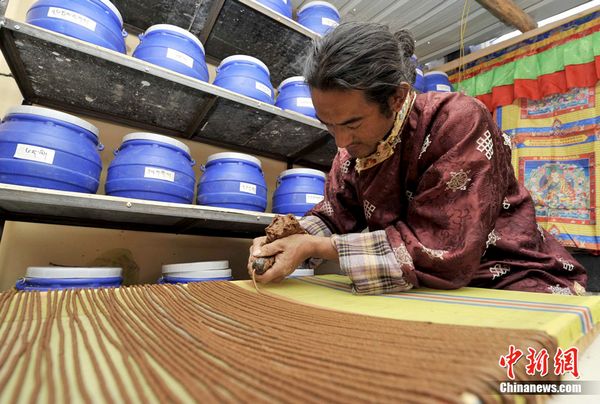 Rinchen Detse, a maker of Tibetan incense, squeezes the Tibetan incense in standard shape by an ox horn in his workshop. [Photo/Chinanews.com]