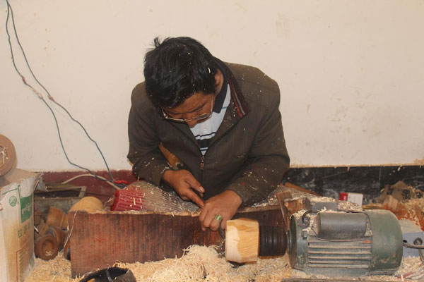 Photo shows a Menba craftsman works on a wooden bowl.{Photo/China Tibet Online}