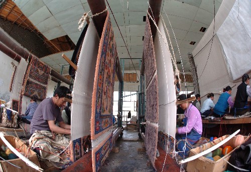 Workers of the Gyangze Carpet Factory are weaving the carpets in the workshop.