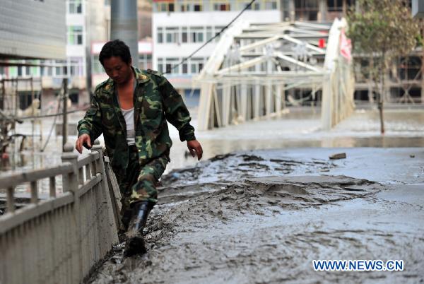 A local resident walks in the mud after the flood retreated in mudslide-hit Zhouqu, northwest China's Gansu Province, Aug. 28, 2010. Rescuers continued the cleaning work at the blocked part of the Bailong River in Zhouqu so that the reserved water could be discharged as soon as possible. Since Aug. 8, more than 400 heavy machine have been deployed in Zhouqu to work almost around the clock to clean the mud at the watercourse. (Xinhua/Liang Qiang)