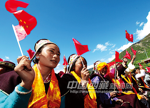 The local people watch art performances while cheer by waving national flags, photo from Tibet Daily.