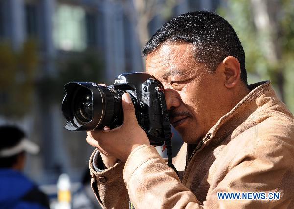 A Tibetan photographer of Tibet's Daily works on an assignment in Lhasa, capital of southwest China's Tibet Autonomous Region, Nov. 8, 2010. China celebrated its 11th Journalist Day nationwide on Monday with a variety of programs and ceremonies.