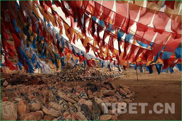 The sutra streamers wave in the air above the colorful Mani Stone. [Photo/China Tibet Online]