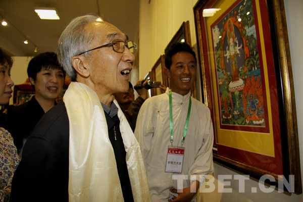 Jin Shangyi, honorary chairman of the China Artists Association, looks attentively at a piece of Thangka painted by young painter Konjo, May 8. [Photo/China Tibet Online]