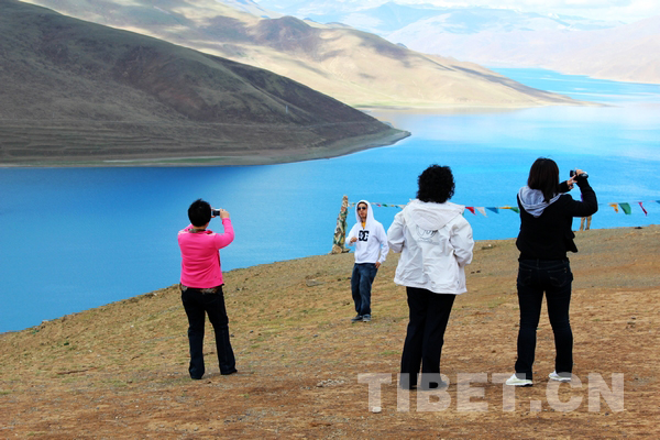 Tourists are taking photo by a holy lake in Tibet. [Photo/China Tibet Online]