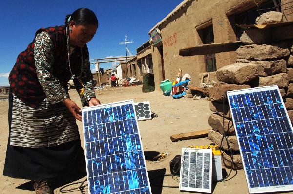 File photo taken on Sep. 23, 2007 shows a herdswoman fixing a solar panel in Burang County of southwest China's Tibet Autonomous Region. [Photo/Xinhua]