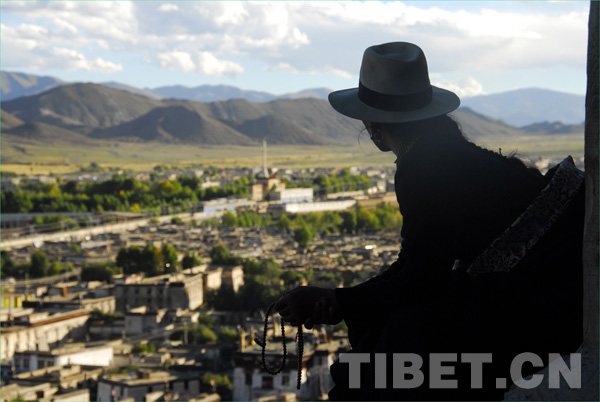 A Tibetan takes a bird view of the township quietly. [Photo/China Tibet Online]