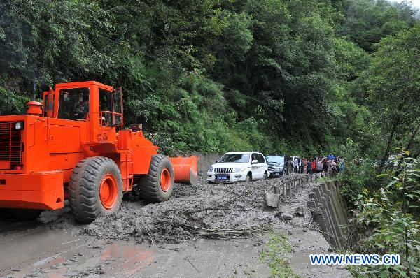 An engineer vehicle clears mud on a highway in Bomi County, southwest China's Tibet Autonomous Region, July 14, 2011. Lasting heavy rainfalls caused mudslides and landslides in five sites along the Sichuan-Tibet highway on Wednesday, blocking traffic in many parts of the road. As of 2:00 p.m. Thursday, traffic has been restored. [Photo/Xinhua]