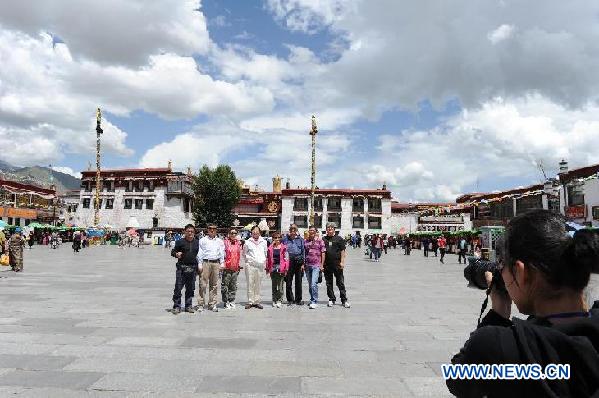 Tourists pose for a photo in the Jokhang Temple Square in downtown Lhasa, capital of southwest China's Tibet Autonomous Region, July 26, 2011. Tourists to Tibet increased by 24.8 percent year-on-year to reach 2.249 million in the first half of this year, according to statistics released by local tourism authority. [Photo/Xinhua]