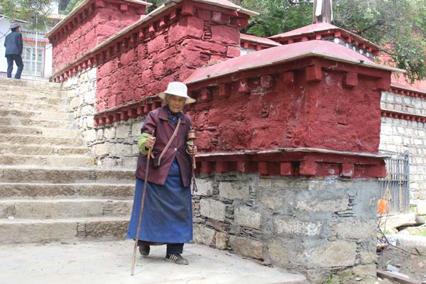 An elder followers steps downstairs inside the Lama Ling Temple.