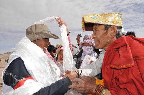 The local Tibetan presents the white hada for the horse rider.[Photo/Xinhua]