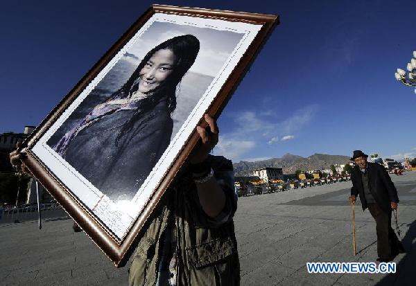 A prize-winning picture of the "Qomolangma photo show" is carried to be displayed at the Potala Palace Square in Lhasa, capital of southwest China's Tibet Autonomous Region, Aug. 27, 2011. The photo show exhibits over 700 pictures showcasing the scenery, portraits and residents' lives in Tibet. [Photo/Xinhua]
