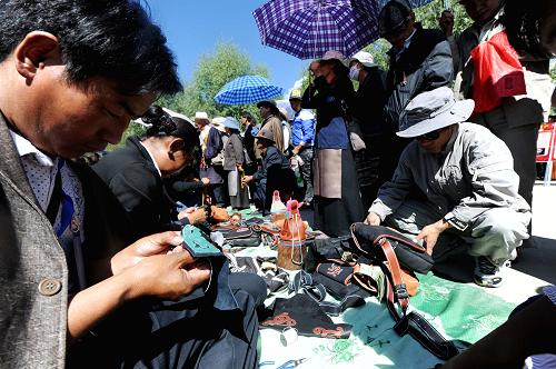 Tsering，successor of the leather-making artistry of Junpa family which was put on the intangible culture heritage list of TAR in 2010, is showing his leather-making skill to audiences Saturday. [Photo/Wen Tao]