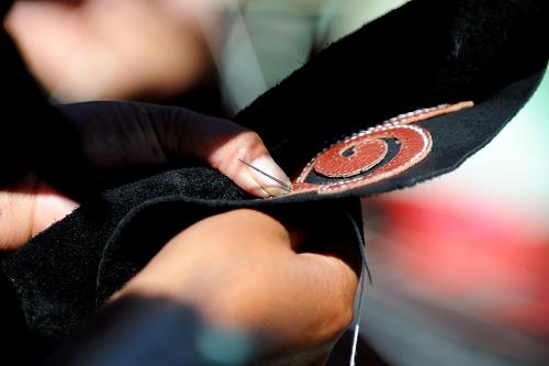 Tsering，successor of the leather-making artistry of Junpa family which was put on the intangible culture heritage list of TAR in 2010, is showing his leather-making skill to audiences Saturday. [Photo/Wen Tao]