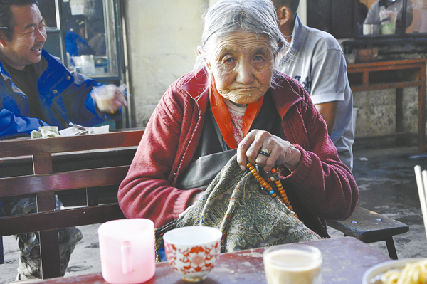 A senior Tibetan enjoys her time in a teahouse of Lhasa. [Photo/Tibetnews.com]