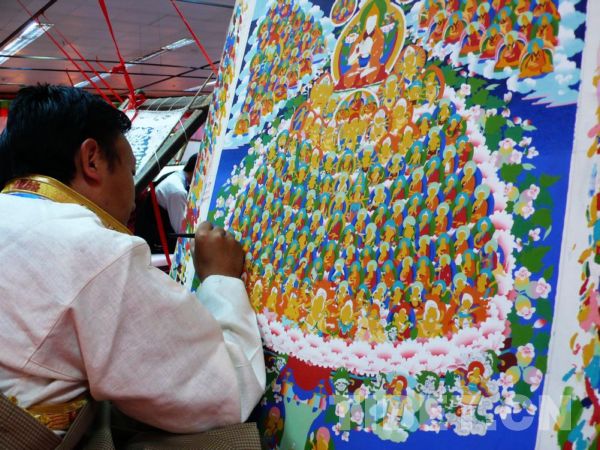 A young Thangka painter works on a new painting composed of over 500 larger or smaller buddhas. [Photo by Rao Chuyan/China Tibet Online]