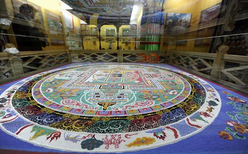 A tourist is visiting Mandala- a Tibetan Buddhist instrument symbolizing the cosmos structure and displayed for worship, October 18, 2011. [Photo/Xinhua]