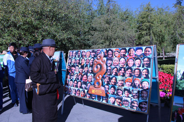 Lhasa residents look at a photo exhibition that displays the local people's well-being October 12, 2011. [Photo/chinadaily.com.cn]