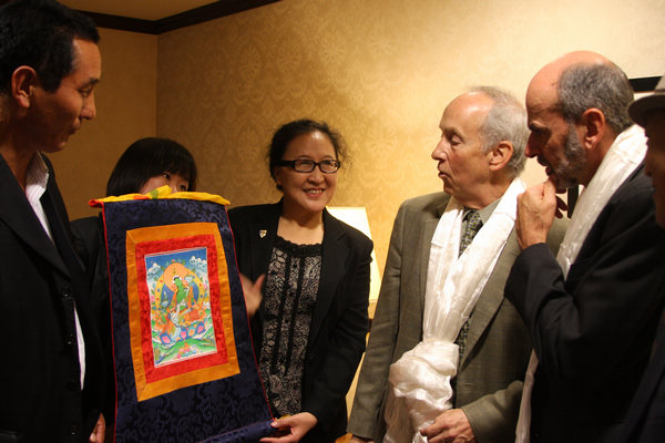 Bi Hua (center), head of the Tibetan cultural delegation, presents a thangka (a Tibetan scroll painting) to Wall Street Journal Washington Bureau Chief Gerald Seib (right) and Senior Editor Bob Davis (second right) after holding a discussion on Tibetan issues on Wednesday in Washington DC. [Tan Yingzi / China Daily]