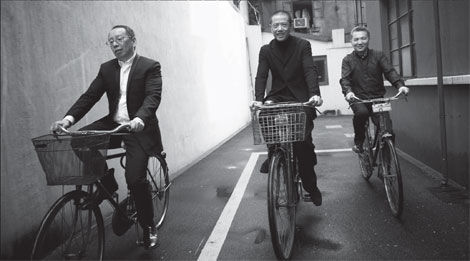  (From left) Lin Xudong, Chen Danqing and Han Xin ride bicycles in Shanghai's narrow lanes to retrace the starting point of their four-decade-long friendship and artistic careers. [Photo by Li Qi /China Daily]