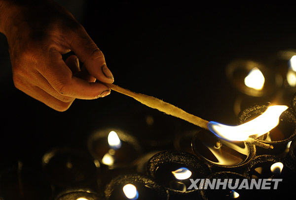 A monk is lighting up butter lamps on the roof of the Johkang Temple. [Photo/Xinhua]