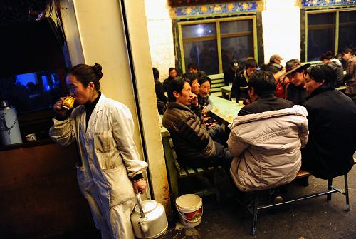 A waiter snatches a little leisure from the busy life in Guangming Kamqung Sweet Tea house on the Tengyeling Road of Lhasa.[Photo/Xinhua]