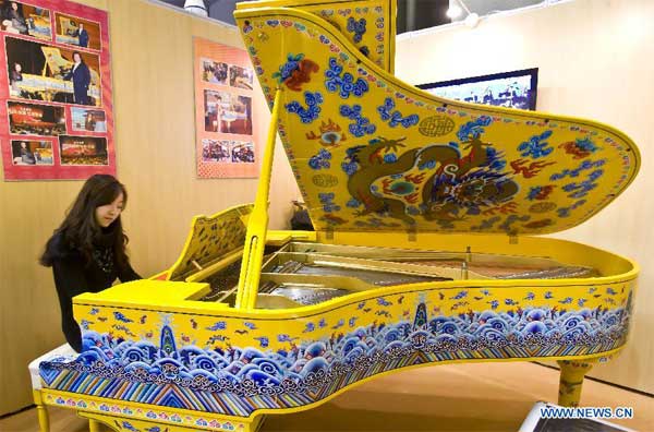 A pianist plays a piano with hand-painted Thangkas, a kind of Tibetan-style painting, made by Beijing Xinghai Piano Group Limited during an exhibition of luxuries in the China World Trade Center in Beijing, capital of China, Dec. 23, 2011.