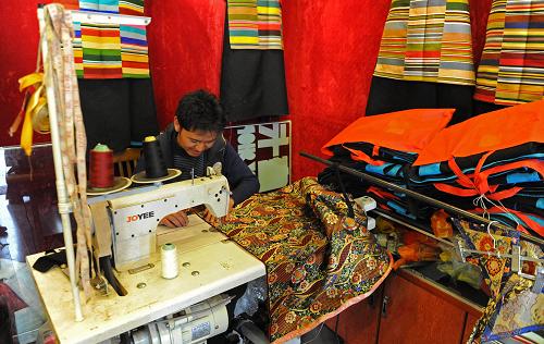 A tailor works at a sewing machine, making costumes for upcoming Losar in his shop in downtown Lhasa on Jan.9.  Losar, the Tibetan new year falls on Feb.22 this year. [Photo/Xinhua]