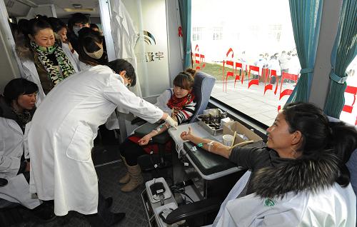 Staff members from Tibet Tibetan Medicine Factory donate blood in a mobile blood-collecting vehicle on Jan. 13, 2012. [Photo/Xinhua]