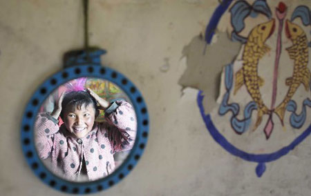 Yangjen puts on makeup in front of a mirror at Rerong Village of Lhongzi County in Shannan Prefecture, south Tibet, Feb. 21, 2009.[Photo/Xinhua]