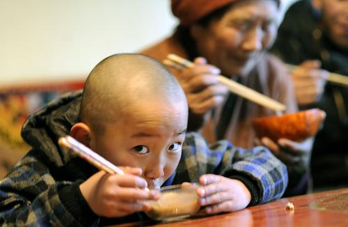 The grandson of a farmer's family is eating Guthuk during family reunion in Dagze County of Lhasa on Feb. 20, 2012. [Photo/Xinhua]