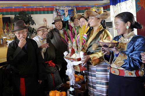 Tibetans take "Chemar", a specialty for Tibetan New Year, Tibetan beer and food to visit neighbors in a community of Lhasa, capital of southwest China's Tibet Autonomous Region on Feb. 22, 2012. [Photo/Xinhua]