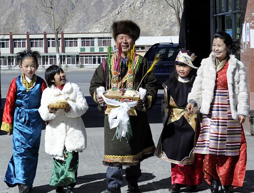 A family is greeting their neighbours with Chemar in a neighbourhood on Losar, Feb. 22.[Photo/Xinhua]