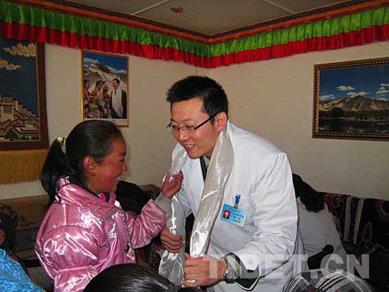A Tibetan girl presents Khada to a doctor for saving her life out of congenital heart disease. [Photo/China Tibet Online]