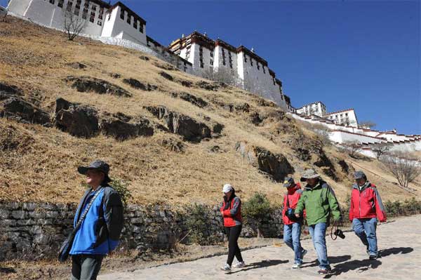 Tourists walk at the foot of the Potala Palace in Lhasa, southwest China's Tibet Autonomous Region, April 12, 2012. The Potala Palace will extend its opening hours during the rush season to meet tourists' demand, the palace's administration said recently. [Photo/Xinhua]