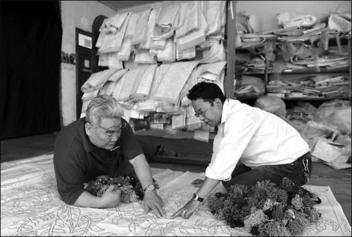 Kesang Tashi discusses with a designer the details of a new carpet.[Photo/China Daily]