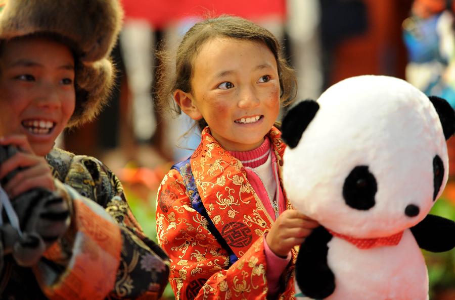 A girl of Tibet ethnic group who is diagnosed with congenital heart disease (CHD) holds a panda doll as she arrives in Hefei, capital of east China's Anhui Province, Nov. 5, 2012.