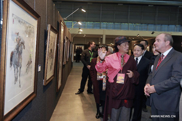 Artist Nyima Cering (2nd R front) of Tibetan ethinc group introduces his works during the 2013 "Beauty of Tibet" Painting and Photography exhibition in Sydney, Australia, May 31, 2013.