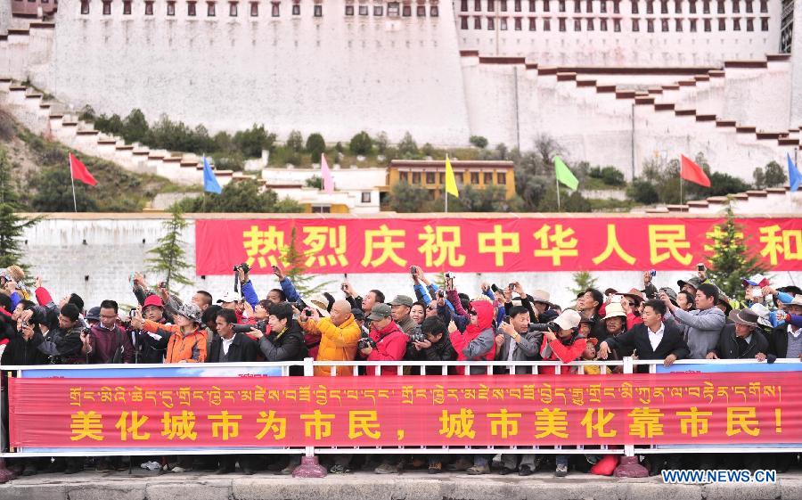 People gather in front of the Potala Palace to watch the flag-raising ceremony in Lhasa, capital of southwest China's Tibet Autonomous Region, Oct. 1, 2013, the 64th anniversary of the founding of the