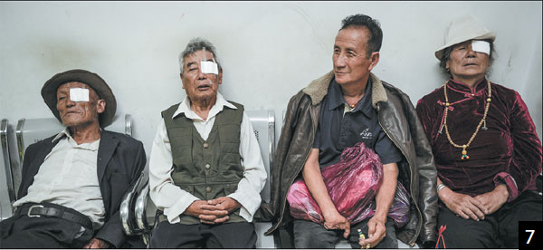 Patients rest in a hospital corridor after receiving cataract surgery from the medical team.