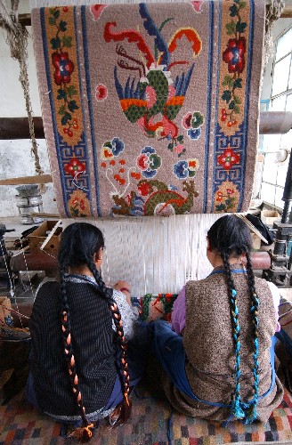 Workers of the Gyangze Carpet Factory are weaving the carpets in the workshop.
