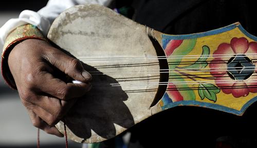 A member of the Farmer Art Troupe is playing Tibetan guitar on Dec. 10, 2011. [Photo/Xinhua]