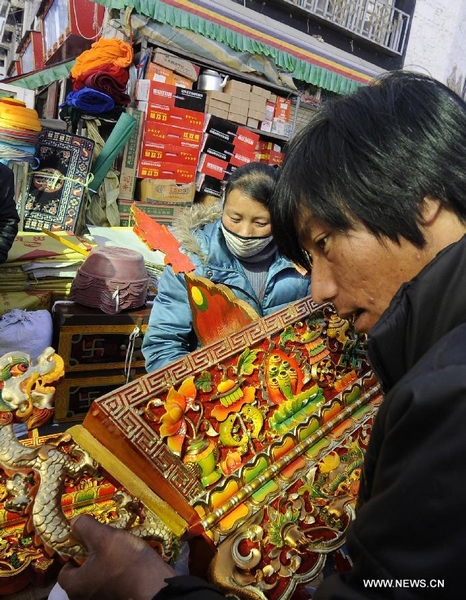 A customer selects a traditional container symbolizing a good harvest at a store in Lhasa, capital of southwest China's Tibet Autonomous Region, Feb. 6, 2012. Local residents of Lhasa started preparing food and home decorations to greet the coming Tibetan New Year, which falls on Feb. 22 this year. People of Tibetan ethnic group are able to enjoy two long holidays in 2012 to celebrate Chinese Lunar New Year and Tibetan New Year respectively. [Photo by Chogo/Xinhua]