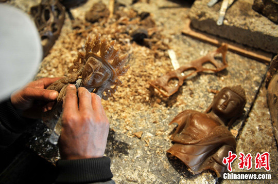 A craftsman repairs the Buddha mould made of beewax in a workshop in Deqen Tibetan Autonomous Prefecture in southwest China's Yunnan Province, on March 20. [Photo/Chinanews.com]