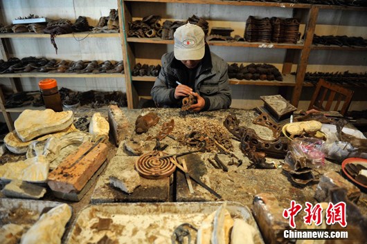 An apprentice engaged in metal craftwork, repairs the Buddha mould made of beeswax, March 20, 2012. [Photo/Chinanews.com]