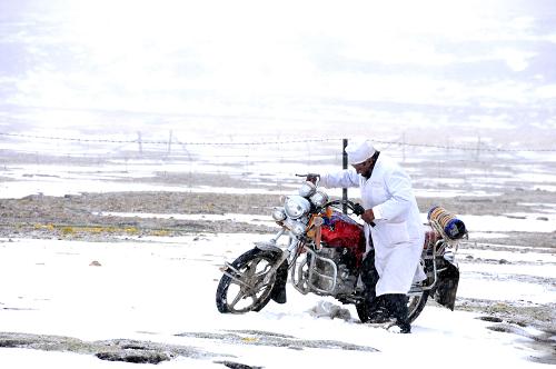 Tsering Banjue's motocycle gets stuck in the snow on the way to visit his patients, June 10, 2011. [Photo/Xinhua]